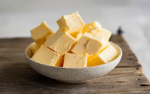 Ein Schälchen voller goldgelber Butterwürfel, bereit für den Einsatz in der Küche. Butter liefert auch etwas Calcium.