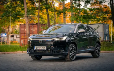 Elegancki, czarny Honda HR-V 2025 na tle jesiennych drzew i kontenerów.