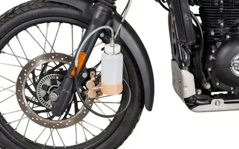 Przygotowanie motocykla do jazdy: odpowietrzanie hamulców z ABS. Widać koło, tarczę hamulcową i zbiorniczek z płynem.
