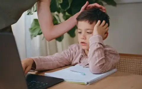 Chłopiec zrezygnowany, gdy dziecko nie chce się uczyć. Rodzic próbuje go pocieszyć, ale bezskutecznie. Może potrzebna pomoc psycholog?