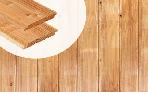 Planches de bois de mélèze ou douglas, avec leurs rainures et languettes, prêtes à être assemblées pour un projet de construction.