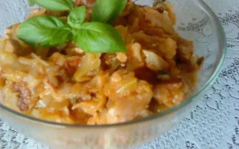 Pyszny bigos ze słodkiej kapusty, duszony z mięsem i przyprawami, udekorowany świeżą bazylią.