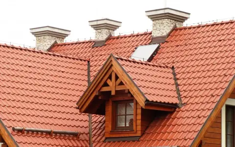 Dach dwuspadowy z czerwonej dachówki, z kominami i lukarną. Instalacja odgromowa zabezpiecza budynek.