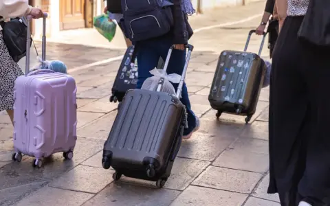 Ludzie z walizkami na kółkach, zastanawiający się, ile dopłata za bagaż Ryanair.