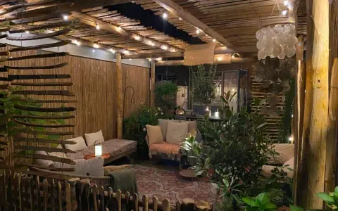 Une terrasse de jardin aménagée en coin cocooning, avec des banquettes confortables, des lumières douces et une ambiance chaleureuse.