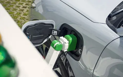 Zielony kabel ładowarki podłączony do portu ładowania samochodu elektrycznego.