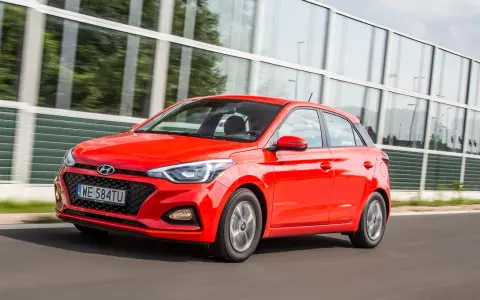Czerwony Hyundai i20 1.2 benzyna w ruchu, z nowoczesną atrapą chłodnicy i światłami.