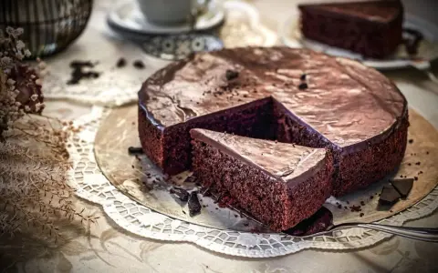 Ein saftiger Schokokuchen mit glänzender Glasur, ein Stück herausgeschnitten. Perfekt für ein Schokokuchen Rezept.