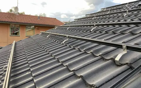 Solpaneler monteras på taket med hjälp av robusta aluminium skenor. Takpannorna är mörka och vågformade.
