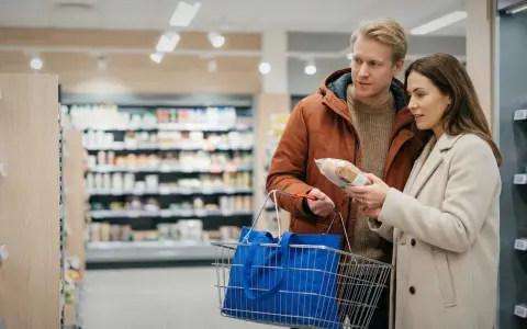 Para dyskutuje o cenach w Szwecji, analizując produkt w sklepie spożywczym.