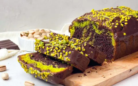 Saftiger Schokoladen-Pistazienkuchen mit Schokoladenglasur und gehackten Pistazien. Die grünen Streifen im Kuchen und die Pistaziencreme machen ihn zu einem besonderen Genuss.