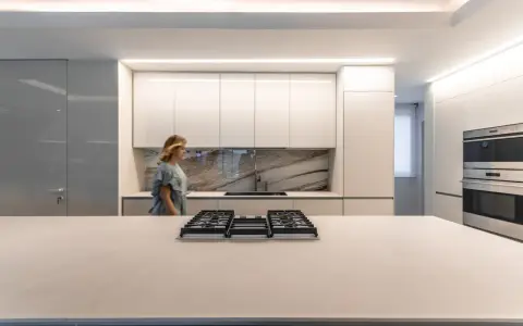 Cocina moderna con iluminación LED integrada en los gabinetes y el techo, ideal para saber como iluminar una cocina.