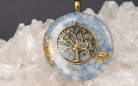 Colgante de orgonita con árbol de la vida dorado sobre fondo de cuarzo. El significado de la orgonita se refleja en su energía protectora.