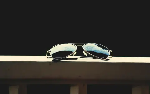 Okulary przeciwsłoneczne typu aviator leżące na drewnianej powierzchni.