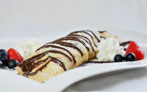 Palatschinken mit Eis, Schokosauce und frischen Beeren. Ein süßer Genuss, der auf der Zunge zergeht.