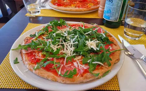 Leckere Pizza mit Rucola und Schinken auf einem Teller, ein Beispiel für glutenfreie Restaurants.