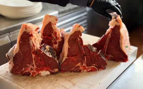Maneggiare con cura la bistecca fiorentina a Firenze, pronta per essere grigliata.