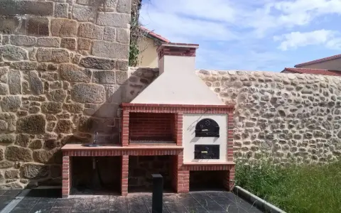 Estupendas ideas para hacer barbacoa de obra: parrilla, horno de leña y fregadero integrados en un diseño rústico junto a muros de piedra.
