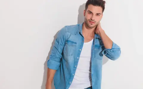 Uomo con un outfit camicia jeans, maglietta bianca e jeans.