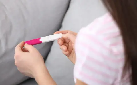 Dłonie trzymające test ciążowy. Wynik wskazuje na 1 miesiąc ciąży, co może być początkiem nowej, pięknej historii.