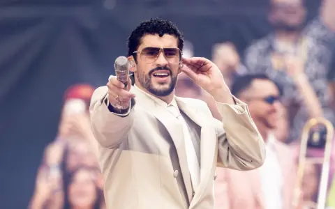 Bad Bunny w beżowym garniturze, z mikrofonem w dłoni, czuje energię tłumu.