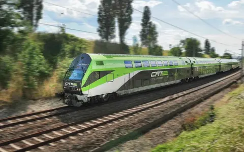 Grön och vit CAT City Airport Train susar fram på spåret, på väg till flygplatsen i Wien.