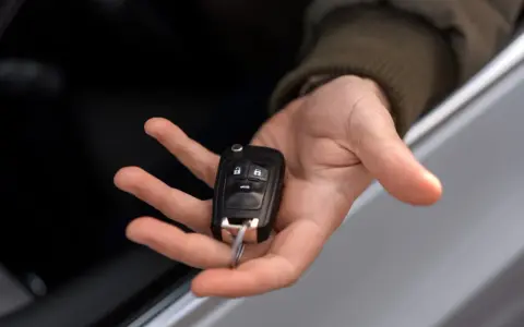 Mano sosteniendo una llave de coche moderna, lista para codificar y arrancar.