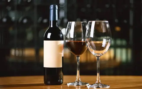 Une bouteille de vin rouge et deux verres, dont un partiellement rempli. Combien de verre dans une bouteille de vin ? La réponse est dans le plaisir de la dégustation.