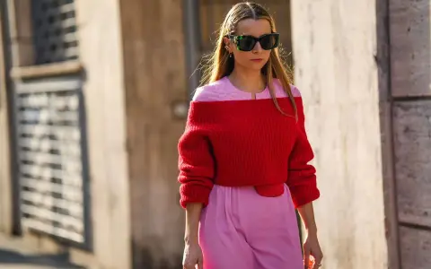 Frau in rotem Off-Shoulder-Pullover und rosa Hose. Eine tolle Farbkombination, die zeigt, welche Farbe passt zu roter Kleidung: Rosa!