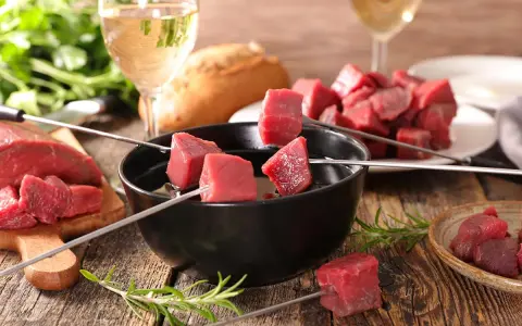 Préparation pour comment faire une fondue bourguignonne : dés de bœuf sur des brochettes, prêts à être plongés dans l'huile chaude.