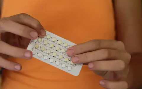Manos sostienen un blíster de pastillas anticonceptivas. Me he quitado el anillo y no me baja la regla, ¿será por esto?