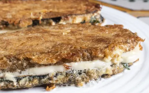 Parmigiana di melanzane ricetta originale: strati dorati e filanti di melanzane fritte, mozzarella e sugo.