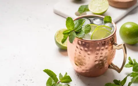 Erfrischender Moscow Mule in Kupferbecher mit Limettenscheiben, Minze und Eis. Perfekt für warme Tage und verschiedene rum sorten.