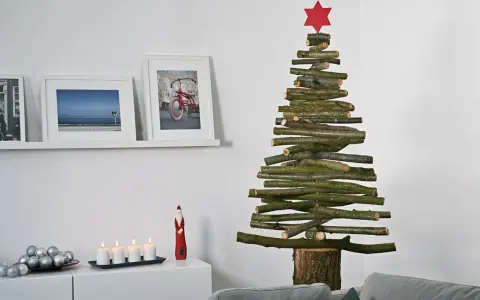 Ein rustikaler Tannenbaum aus Holzlatten, selbstgemacht, mit rotem Stern. Daneben Bilder und Kerzen.