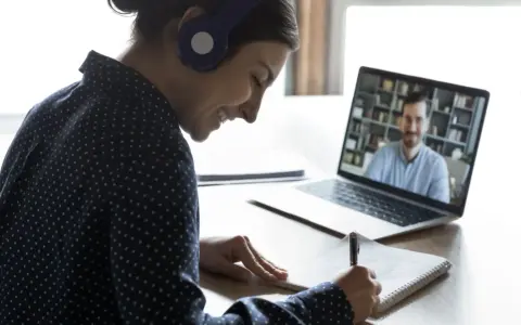 Ragazza con cuffie sorride mentre prende appunti durante una lezione online, comprendendo il vero e-learning significato.