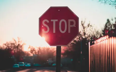 Czerwony znak STOP na tle zachodzącego słońca. Przypomina, do czego są wykorzystywane listy kontrolne: do zatrzymania się i sprawdzenia, czy wszystko jest w porządku.