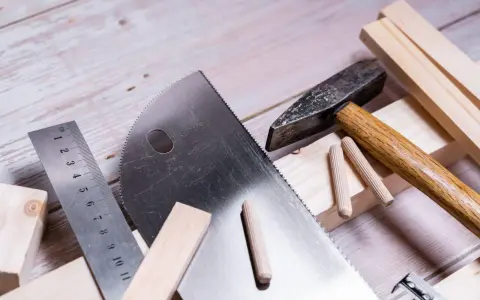 Herramientas para trabajar la madera: sierra, martillo, regla y tacos de madera listos para un proyecto.