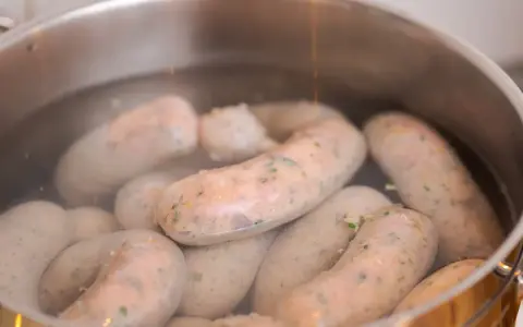 Biała kiełbasa gotuje się w garnku. Poznaj prosty sposób, jak parzyć białą kiełbasę, by była idealna.