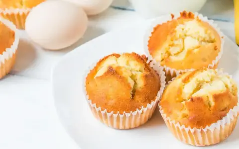 Puszyste babeczki z airfryer na białym talerzu, obok jajka. Idealne na szybkie śniadanie.