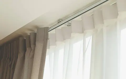 Detalle de rieles para cortinas, mostrando diferentes tipos de tela y su sistema de sujeción al techo.