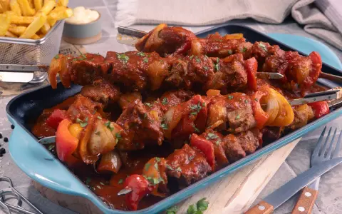 Herzhaftes Schaschlik im original Rezept-Stil, mit saftigem Fleisch, Paprika und Zwiebeln in würziger Sauce. Dazu knusprige Pommes.