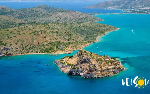 Kreta, lipiec: słoneczna pogoda i turkusowe morze otaczają skalistą wyspę z ruinami fortecy.