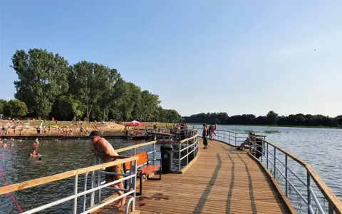 Ludzie odpoczywają i kąpią się nad zalewem Borki. Drewniane molo zaprasza do spacerów i podziwiania widoków.