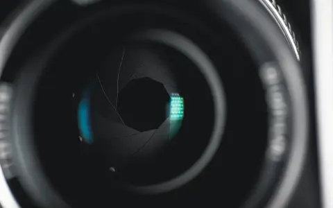 Ouverture d'objectif de caméra, diaphragme réglé sur f 2.8, révélant des reflets bleus et verts.
