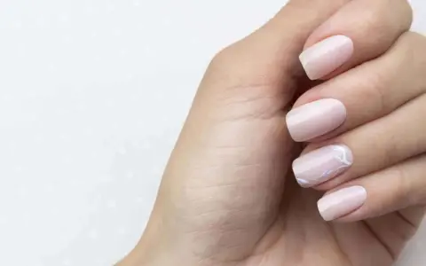 Main gauche avec des ongles pastel, dont un orné d'un motif floral délicat. Parfait pour faire les ongles.