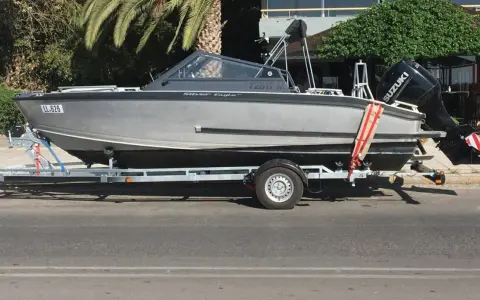 Ein graues Boot, "Silver Eagle", wird auf einem Anhänger transportiert. Der Suzuki Außenbordmotor ist montiert.