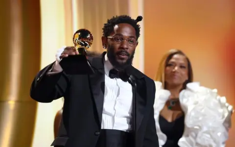 Artysta w garniturze odbiera nagrodę Grammy: najlepsza piosenka - rap.