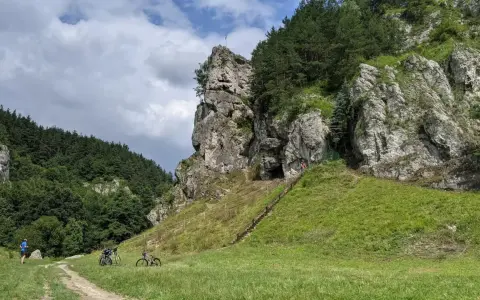 Dolina Kobylańska zachwyca skalnymi formacjami i zielonymi zboczami. Na ścieżce rowerzyści, a na skałach wspinacze.
