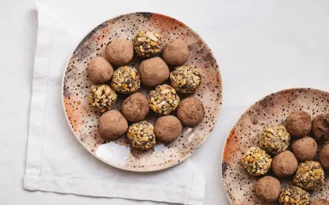 Plato con trufas de chocolate espolvoreadas con cacao y otras cubiertas de frutos secos.