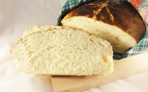 Pyszny, domowy chleb wielkanocny, pokrojony w kromki, z chrupiącą skórką i puszystym wnętrzem, owinięty w tradycyjny ręcznik.
